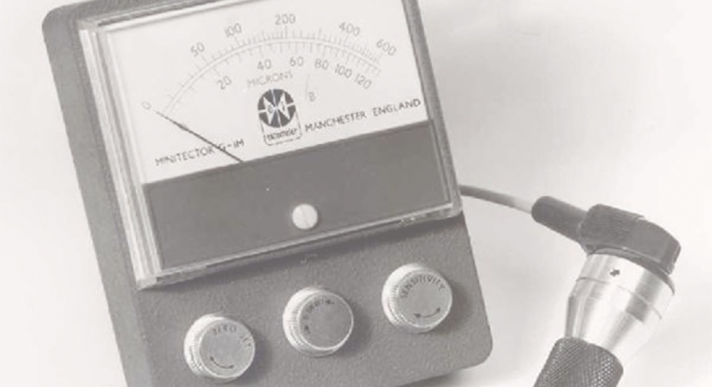An Elcometer Minitector analogue coating thickness gauge marked in microns, with probe