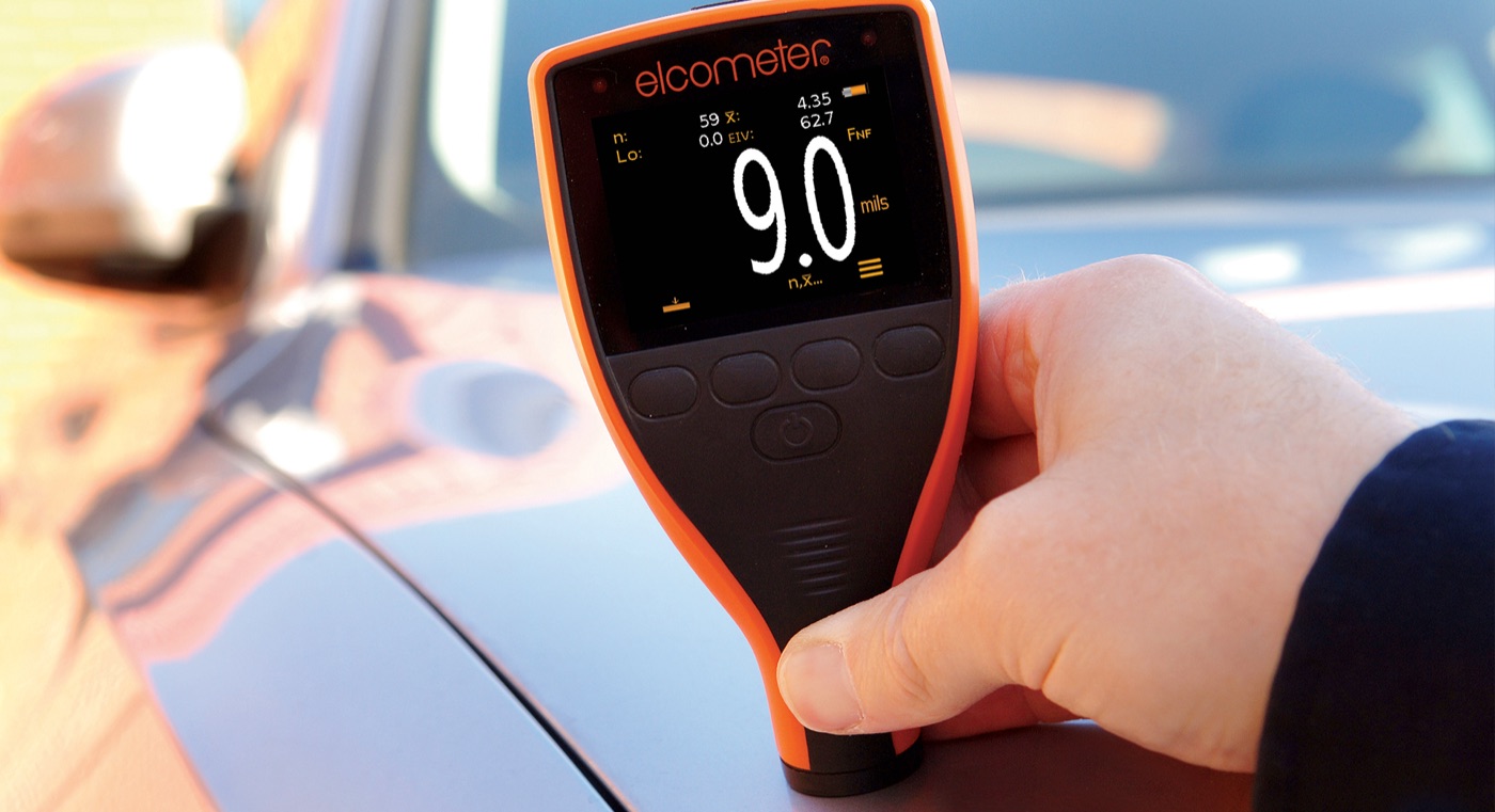 An Elcometer automotive coating thickness gauge reading 9.0 mils on a car panel