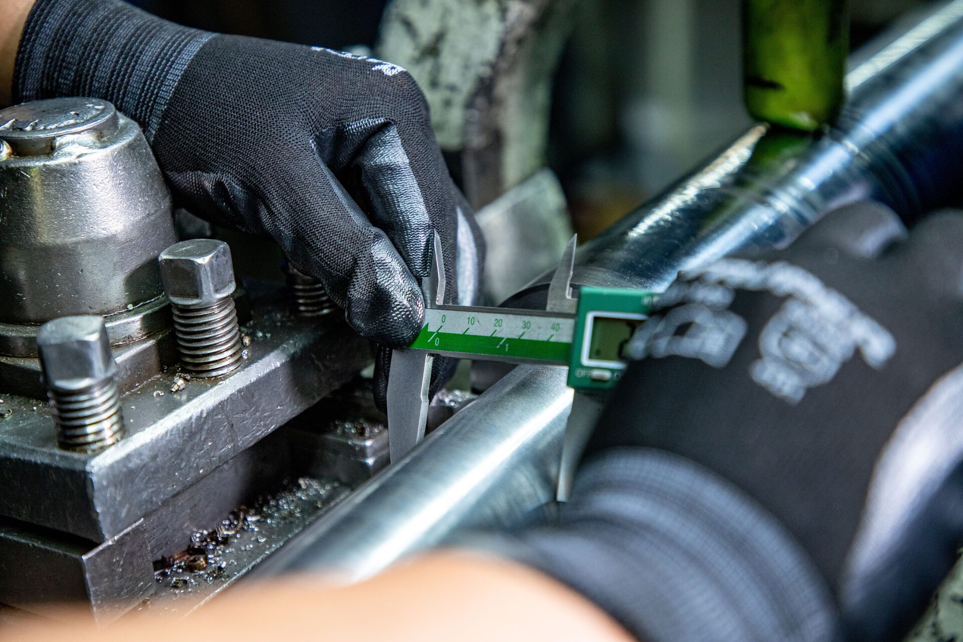 Quality-control inspector measuring a machined component with a digital caliper